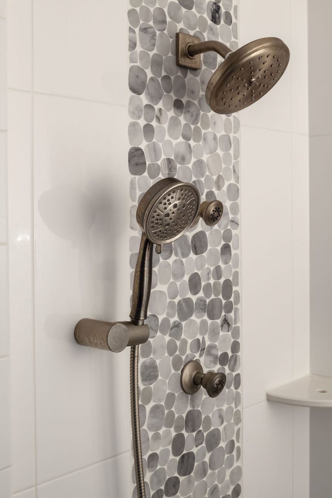 Multiple custom shower heads and pebbled mosaic tiles