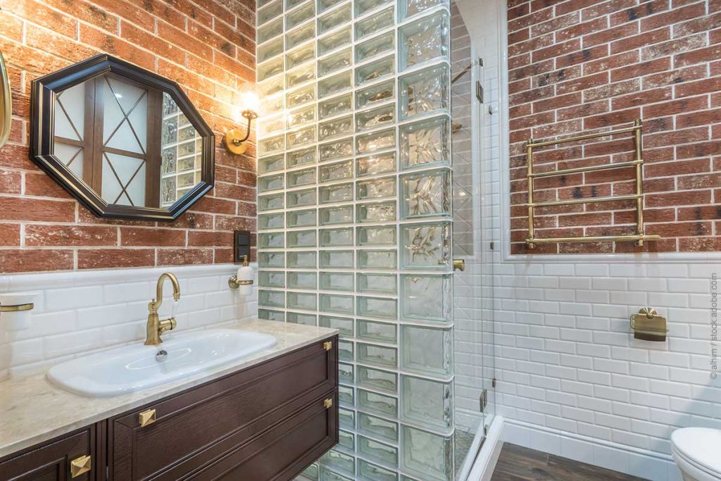 Stylish bathroom design trends, decorated with brick tiles. The wall of the shower are made of glass blocks.